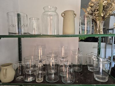 de nombreux verres et vases posés sur une étagère dans une pièce