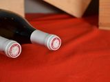 two bottles of wine sitting on a red cloth