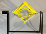 une image représentant une sculpture jaune et noire posée sur une surface blanche