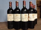 several bottles of wine are lined up on a wooden table