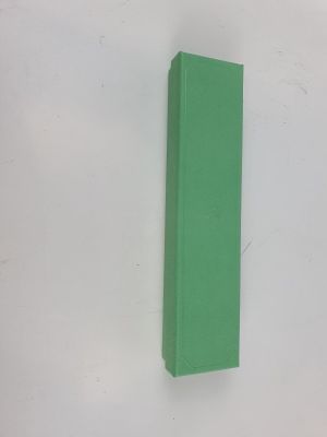 un livre vert posé sur une surface blanche, près d'un mur blanc