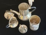 une théière et des tasses en argent posées sur une table noire