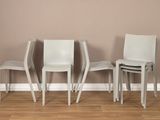 trois chaises blanches placées devant un mur marron dans une pièce