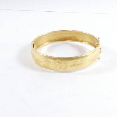 gros plan d'un bracelet en or sur une surface blanche