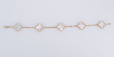 un bracelet en or orné de quatre breloques en forme de trèfle sur fond blanc