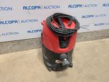 a red and black vacuum cleaner sitting on top of a cement floor