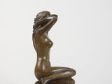 a statue of a woman sitting on a rock with her hands behind her head
