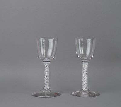 pair of clear wine glasses with silver rims on a grey background