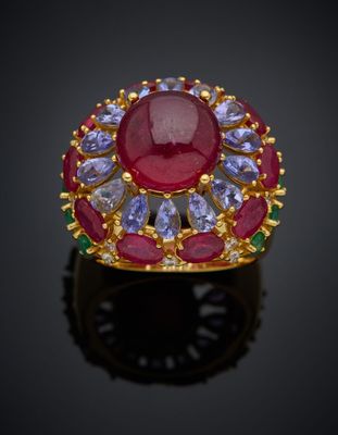 un gros plan d'une bague ornée d'une pierre rouge entourée de pierres bleues et vertes