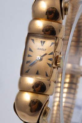 a gold bracelet watch with three balls on it