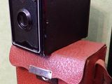 un petit appareil photo marron posé sur une valise rouge