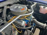 une voiture bleue avec un gros moteur dans le coffre