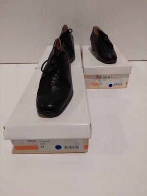 une paire de chaussures en cuir noir pour homme posée sur des cartons