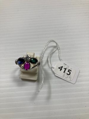 un gros plan d'une bague en argent sertie de pierres violettes et vertes