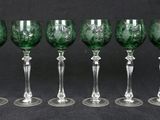 six green wine glasses lined up in a row on a black background