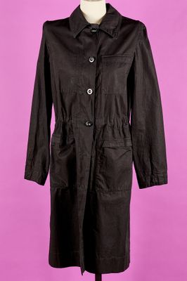un manteau noir posé sur un mannequin, devant un fond rose