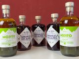Des bouteilles d'huile d'olive et de vinaigre sont posées sur un plan de travail devant un mur rouge
