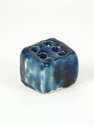un petit objet bleu percé de trous, posé sur une surface blanche