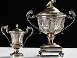 two silver vases sitting on top of a table next to each other