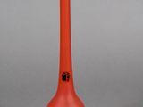 un vase en verre orange avec un couvercle noir, posé sur une surface blanche
