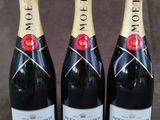 trois bouteilles de champagne Moët & Chandon sur fond gris