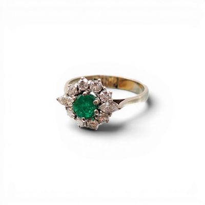 un gros plan d'une bague en diamant verte et blanche sur fond blanc