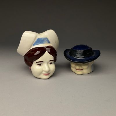 deux figurines en céramique représentant des femmes coiffées de chapeaux