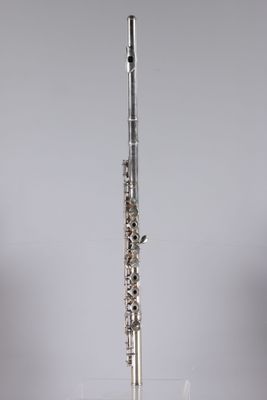 a silver flute sitting on top of a table next to a glass