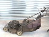 an old lawn mower sitting on the ground in front of a garage door