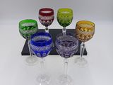 six verres à vin de couleurs différentes posés sur un plateau noir