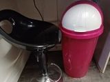 a black chair and a red trash can under a kitchen counter