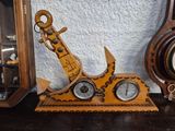 a wooden clock with an anchor on it and a clock on a shelf