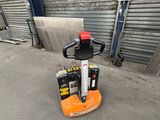 an orange and black forklift parked in front of a garage