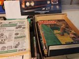 two boxes of books on a table next to a box of magazines