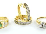 trois bagues en or serties de diamants et d'émeraudes sur fond blanc