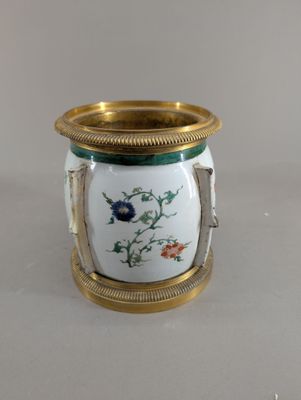 un vase blanc orné d'un liseré doré et d'une fleur bleue