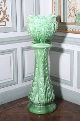 un vase vert posé par terre devant un mur