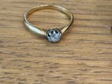 a gold ring with a diamond on top of a wooden table