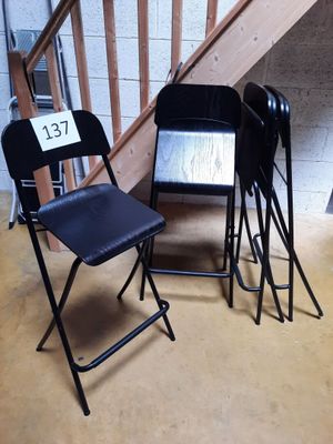 trois chaises pliantes noires placées les unes à côté des autres dans une pièce