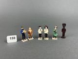 cinq figurines représentant des personnages en tenues variées sont disposées à côté d'une étiquette de prix