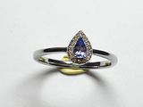un gros plan d'une bague sertie d'un saphir beige en forme de poire, entouré de diamants