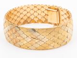 a close up of a gold bracelet on a white background