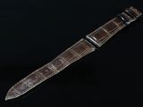 une image représentant une montre avec un bracelet en cuir marron sur un fond noir