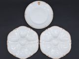 trois assiettes blanches aux bords dorés posées sur un fond noir