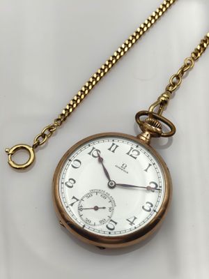 an image of a gold pocket watch with a chain on a white surface