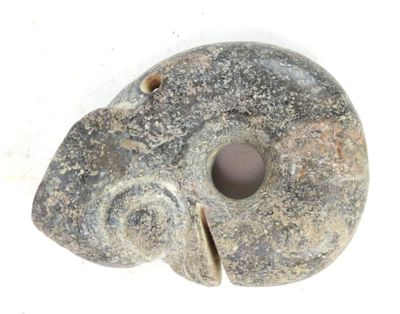un objet en pierre percé d'un trou, posé sur une surface blanche