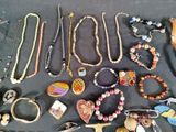 many different necklaces and bracelets laid out on a table