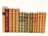 several old books are lined up in a row on a white surface