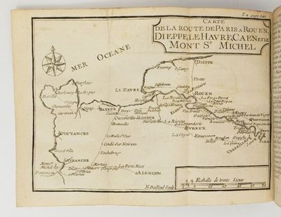 un livre ouvert, sur lequel figure une carte, posé sur une table