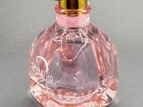 pink perfume bottle with a gold lid on a gray surface